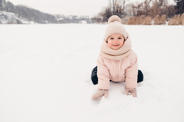 Canvas Print - Happy laughing girl wearing a pink jacket, scarf and hat, playing in a beautiful snowy winter walk. Girl enjoys winter, frosty day. Playing with snow on winter holidays. Winter holidays concept.