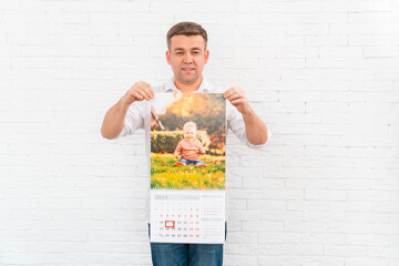 Wall Mural - man holds a calendar with a photo of a child in front of him. printed products.