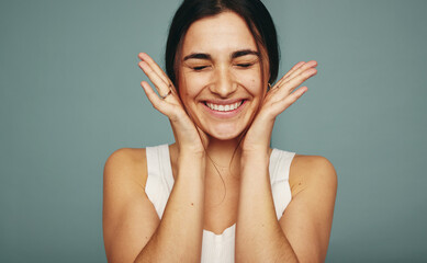 Excited young woman smiling with her eyes closed in a studio