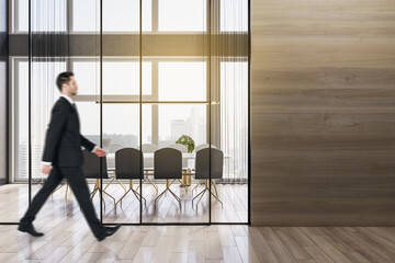 Sticker - Businessman walking in modern wooden meeting room office interior with empty mock up place on wall, table, armchairs, window with city view and daylight. Workplace and law and legal concept.