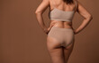 Rear view of female body with flaws and imperfections isolated on beige background with copy ad space. Body positivity, love to your body, self-confidence and the concept of self-acceptance