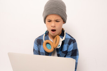 Wall Mural - Shocked boy wearing casual clothing sitting on floor holding laptop computer isolated over white background.