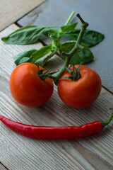 The smiling face is made of vegetables on the wooden background. Two tomatoes and one red pepper are lying on the wood. Red healthy food