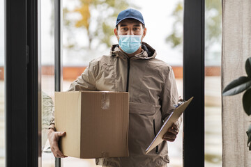 Sticker - health protection, mail service and pandemic concept - delivery man in face protective mask holding parcel box with clipboard at open door