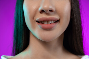 Cropped portrait of beutiful female mouth, full lips isolated over purple background. Beauty and cosmetology treatment