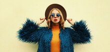Fashionable Portrait Of Stylish Young Woman, Female Model Posing Wearing A Blue Faux Fur, Round Hat On Background