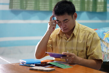 Asian man feels serious and holds and looks at book bank account. Concept : Budget management. Planning to invest  for future life and daily life during  bad economy.  