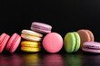 Colorful cake macaron or macaroon on black background. Flat lay, top view, copy space