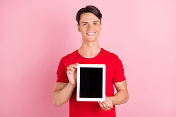 Sticker - Photo of attractive cute young man wear red t-shirt smiling holding modern gadget empty space isolated pink color background