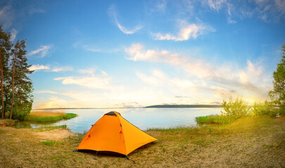 Wall Mural - orange tourist tent on river bank on sunny day