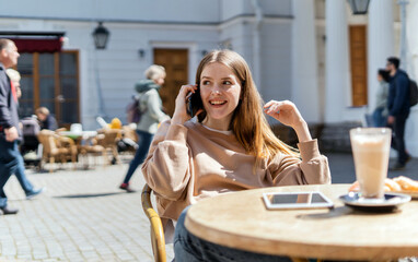 Hipster surfs the internet on his phone. Millennial woman smiling young hipster working on laptop in cafe.