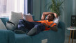 © Framestock - African American man in orange waistcoat yawning while lying on sofa and sleeping after work in daytime at home