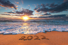 Happy New Year 2022 Concept, Lettering On The Beach. Written Text On The Sea Beach At Sunrise.