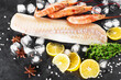Cod shrimp background. White fish fillet, frozen shrimps on a dark background with lemon, ice, anise and thyme.