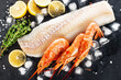 Cod shrimp background. White fish fillet, frozen shrimps on a dark background with lemon, ice, anise and thyme.