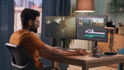 Wall Mural - unrecognizable man in orange t shirt using computer to edit video while sitting at table and working