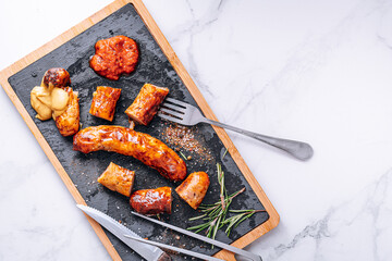 Wall Mural - fried sausages with sauces and spices on a stone plate