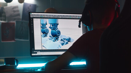 Anonymous teenager in headphones making 3D model of robot on computer while creating cartoon at night at home