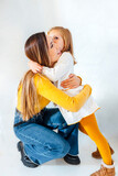 Fototapeta Na drzwi - Young business mother hugging her daughter on white background. Young hispanic woman. Mum and daughter concept.