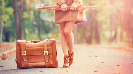 Wall Mural - Gril in coat with umbrella and suitcase in the park.