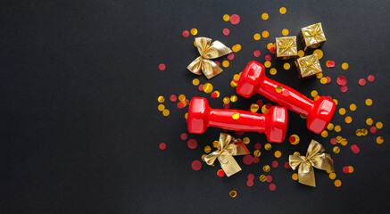 Wall Mural - Exercises, fitness and concept development merry Christmas and Happy New Year. Red dumbbells, bows and golden gifts on a black background with confetti. Flat lay, top view, copy space, banner