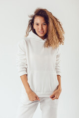 smiling woman with thick curly hair in a white suit of hoodies and sweatpants.