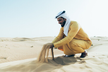 Wall Mural - Man wearing traditional uae clothes spending time in the desert