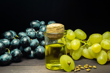 Grape oil seed in small vintage bottle. Heap of grape seeds with green slices and cold press organic essential oil, tincture, extract, infusion on wooden rustic background closeup