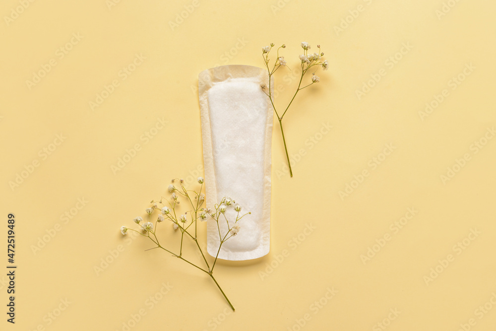 Menstrual pad and flowers on yellow background