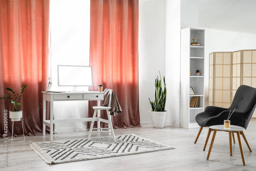 Interior of light room with modern workplace and red curtains