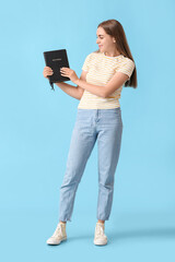 Wall Mural - Pretty young woman with Holy Bible on blue background