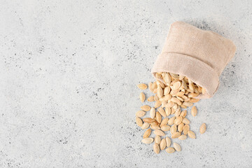 Wall Mural - Bag with natural pumpkin seeds on light background