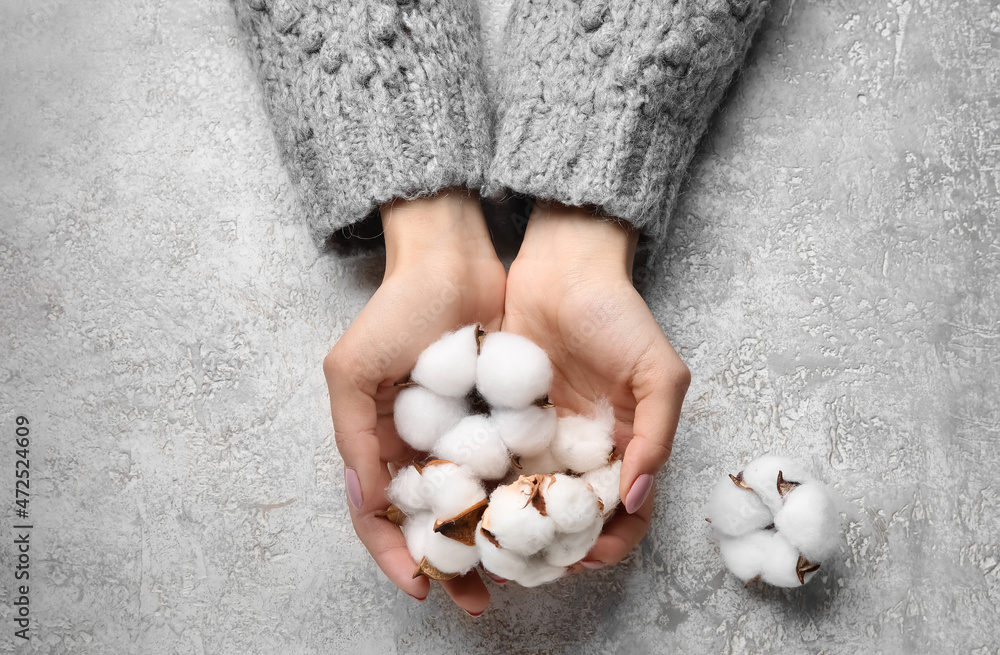 Female hands with cotton flowers on grunge background