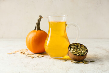 Jug with pumpkin seed oil on light background