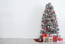 Beautiful Christmas Tree And Gift Boxes Near White Wall