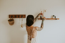 Woman Placing Aroma Diffuser On Wall Shelf