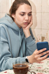 A beautiful brunette with long hair combed back looks into her smartphone