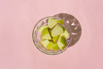 Wall Mural - Apple cut inside a glass container on a pink background