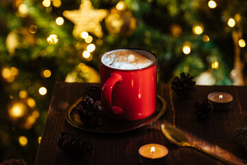 Wall Mural - Cup of pumpkin spice late in a rustic moody and vintage Christmas atmosphere and Christmas lights and tree in blurry background