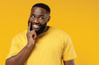 Young smiling wistful minded happy black man 20s wearing bright casual t-shirt look aside prop up face chin choose isolated on plain yellow color background studio portrait. People lifestyle concept.