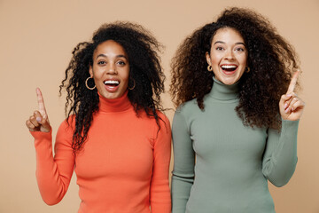 Canvas Print - Two insighted smart proactive young curly black women friends 20s wearing casual shirts clothes holding index finger up with great new idea isolated on plain pastel beige background studio portrait.