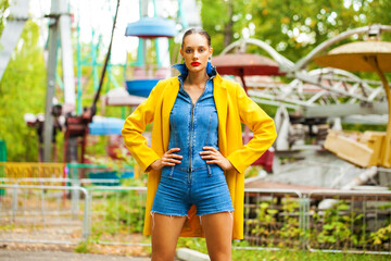 Wall Mural - Young woman in yellow coat and denim overalls