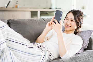 部屋でスマホを使う若い女性