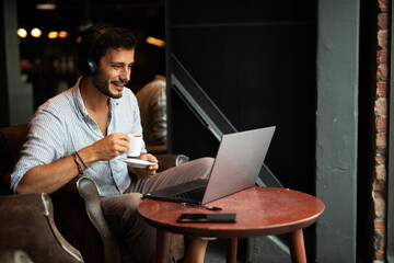 Handsome businessman working on laptop and sitting in cafe. Young student learning online.