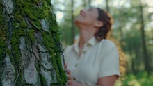 Woman Gently Touches Tree Bark In Forest With Hand.Nature Lover Woman Loves An Old Tree Covered With Moss With Her Hand On A Sunny Summer Day. Concept Of Woman's Love Of Nature.