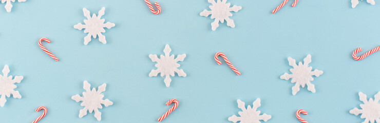 Wall Mural - Christmas composition. Banner made of snowflakes, red and white candies on blue background. Christmas, winter, new year concept. Minimal style. Flat lay, top view