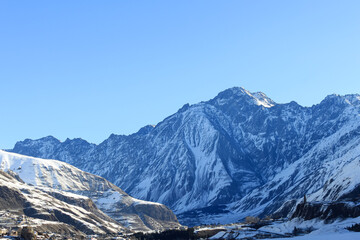 A snowy mountain range against a clear blue sky. Morning mountain scenery.