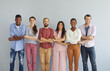 © Studio Romantic - Studio group portrait of happy young diverse friends. Smiling millennial mixed race people holding hands and looking at camera standing isolated on light background. Community and support concept