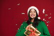 © Drobot Dean - Young woman in Christmas hat posing with present box and confetti