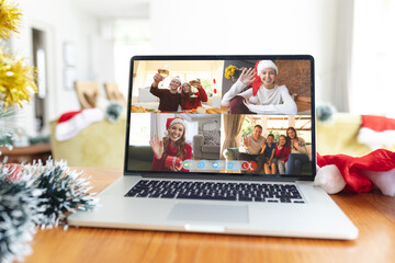 Wall Mural - Happy caucasian family members waving and raising glasses on laptop video call screen at christmas